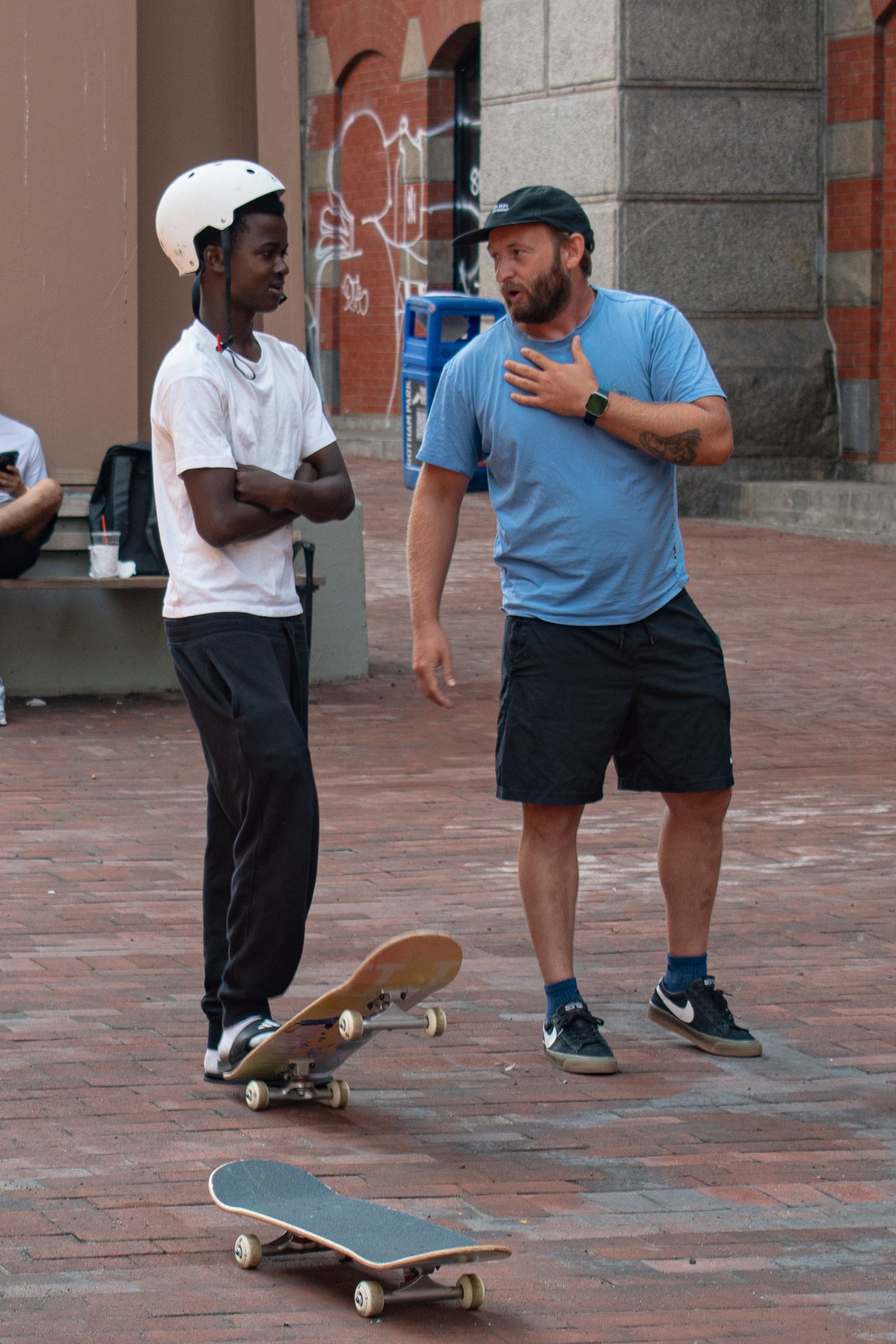 Two adults in conversation beside the brick bank, boards at their feet.